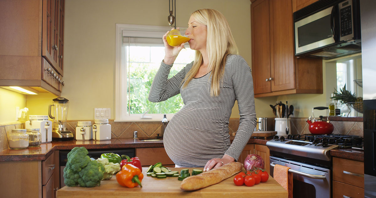 Happy Pregnant woman drinking juice